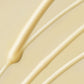 Nahaufnahme mehrerer dicker, cremefarbener, beigefarbener Flüssigkeitslinien, die der Formel des Deep Breakout Liquid Patch ähneln und auf einer glatten, hellen Oberfläche verteilt sind.