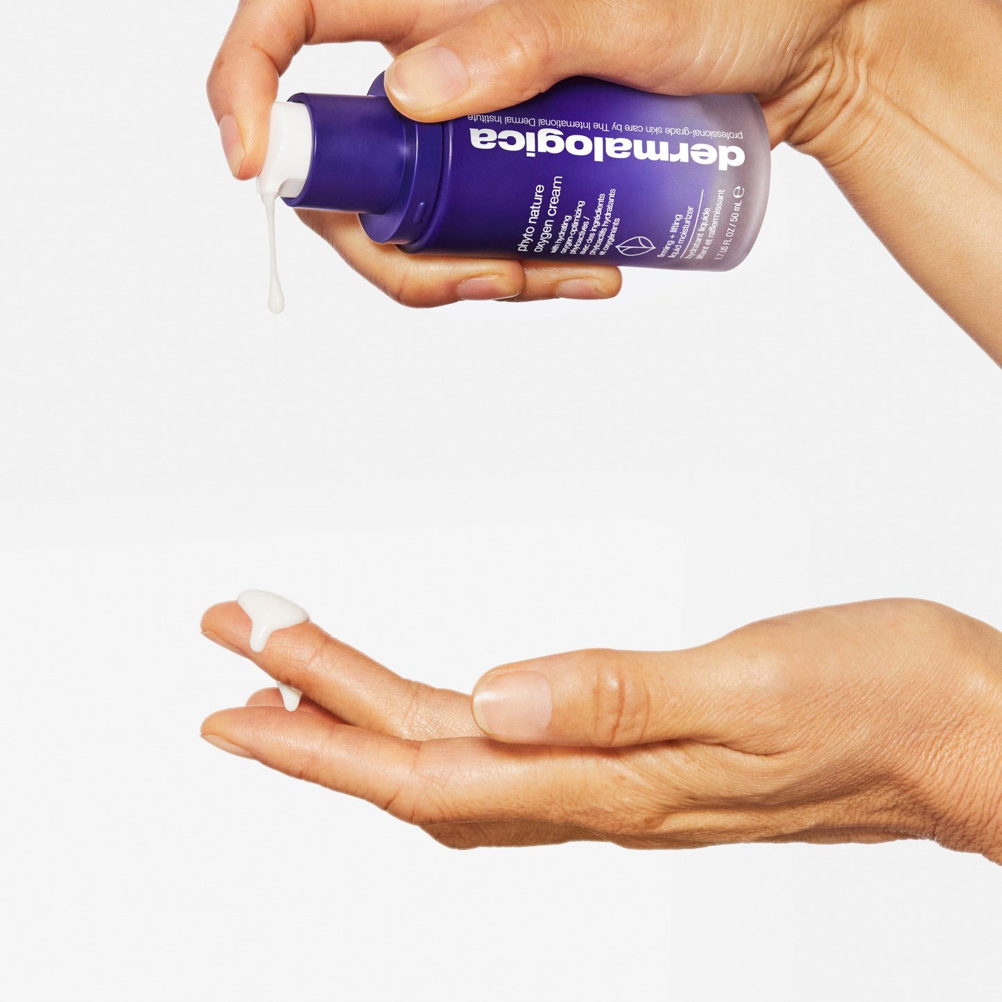Eine Hand verteilt weiße Creme aus einer lilafarbenen Phyto Nature Lifting Eye Cream + Phyto Nature Oxygen Cream Flasche auf die Finger einer anderen Hand und hebt die straffende Wirkung der Creme vor einem klaren weißen Hintergrund hervor.