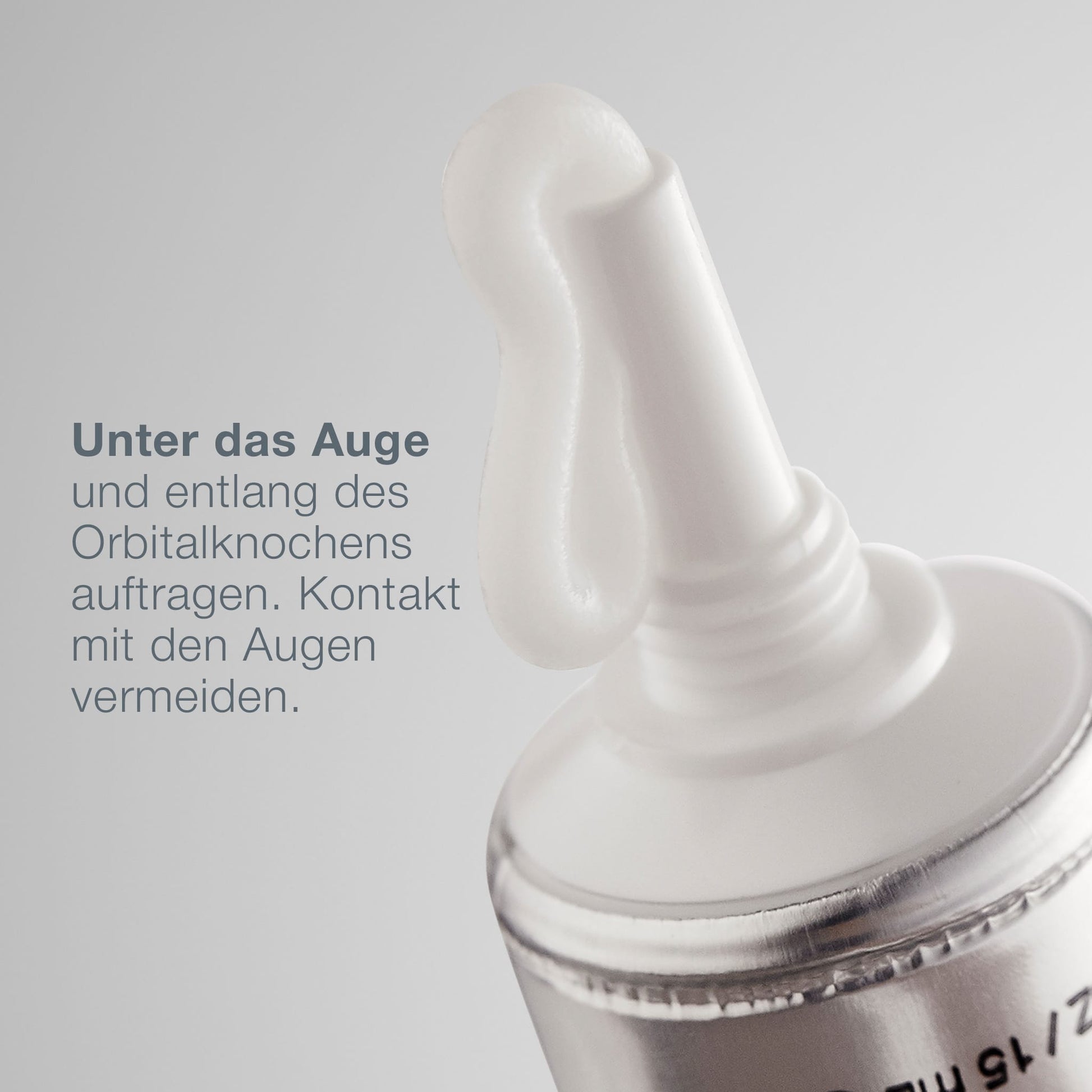 Nahaufnahme einer MultiVitamin Power Firm Tube, die Creme spendet, mit deutscher Anleitung zur Anwendung unter dem Auge und entlang des Augenhöhlenbeins. Enthält einen Vitaminkomplex für gezielte Anti-Aging-Pflege; direkten Augenkontakt vermeiden.
