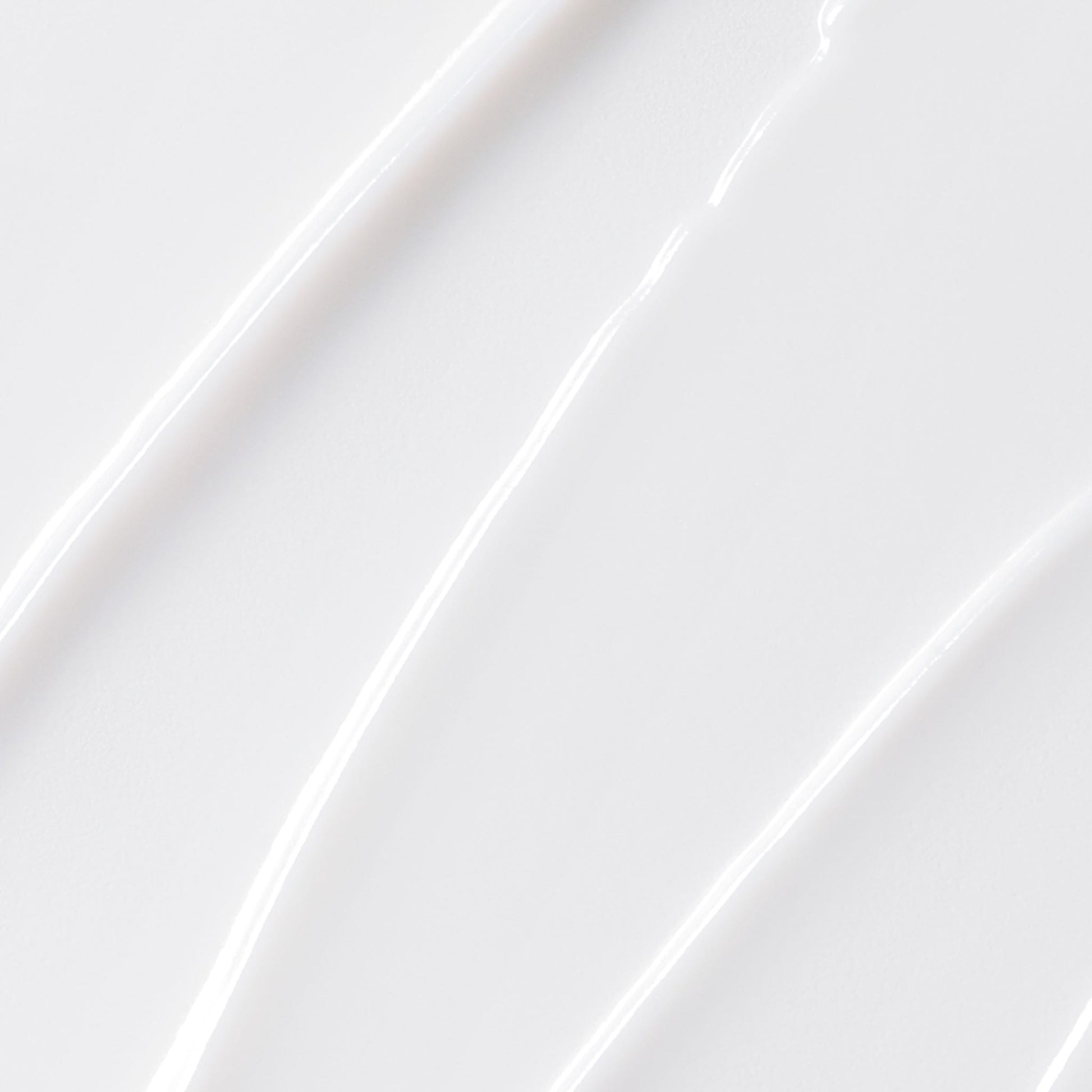 Nahaufnahme der glatten, weißen MultiVitamin Power Firm Anti-Aging-Creme, die in gleichmäßigen, strukturierten Linien auf einer ebenen Fläche verteilt ist.