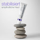 Eine Tube „Stabilizing Repair Serum“, die auf grauen Steinen balanciert, im Hintergrund die Aufschriften „stabilisiert empfindliche Haut“ und „Hautbarriere stärken“.
