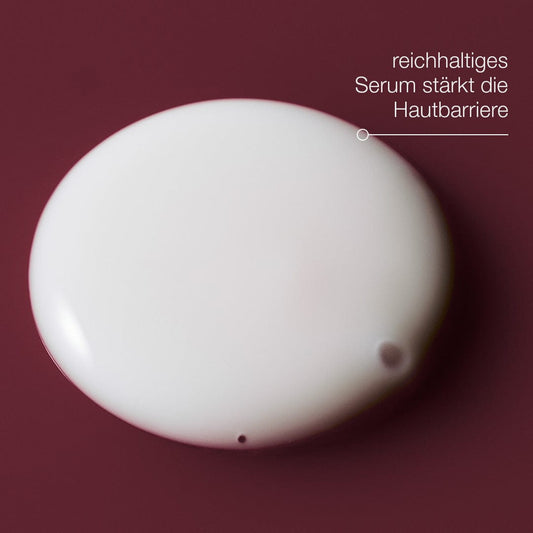 Ein Tropfen Dynamic Skin Strengthening Serum auf dunkelrotem Hintergrund mit deutschem Text betont die BioShield-Technologie, die die Vorteile der Hautbarriere verbessert.
