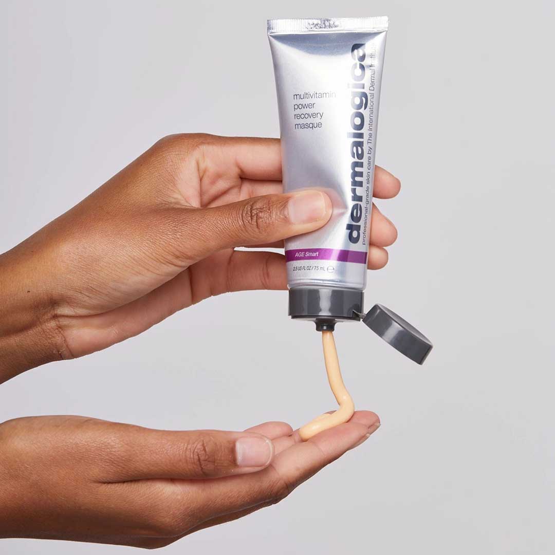 Eine Person drückt eine Tube MultiVitamin Power Recovery Masque, Teil des Stressed Skin Recovery System Sets, und gibt das Produkt auf ihre Handfläche.