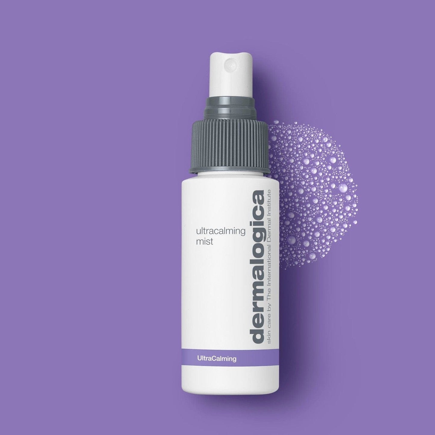 Eine weiße Flasche Routine Frühlingshaut mit einer grauen Sprühkappe ist auf einem lila Hintergrund abgebildet, ideal für empfindliche Haut, mit einem Sprühnebeleffekt auf der rechten Seite.