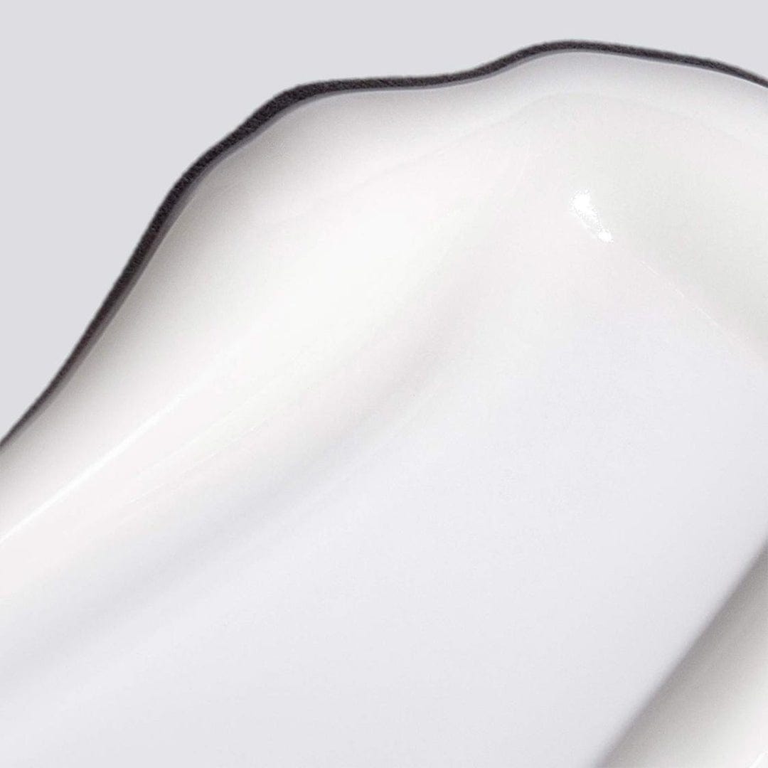 Nahaufnahme der Ecke einer weißen Keramikschale mit gewelltem, schwarz umrandeten Rand, die das innovative Design des Smart Response Serums von Dermalogica widerspiegelt, vor einem hellgrauen Hintergrund.