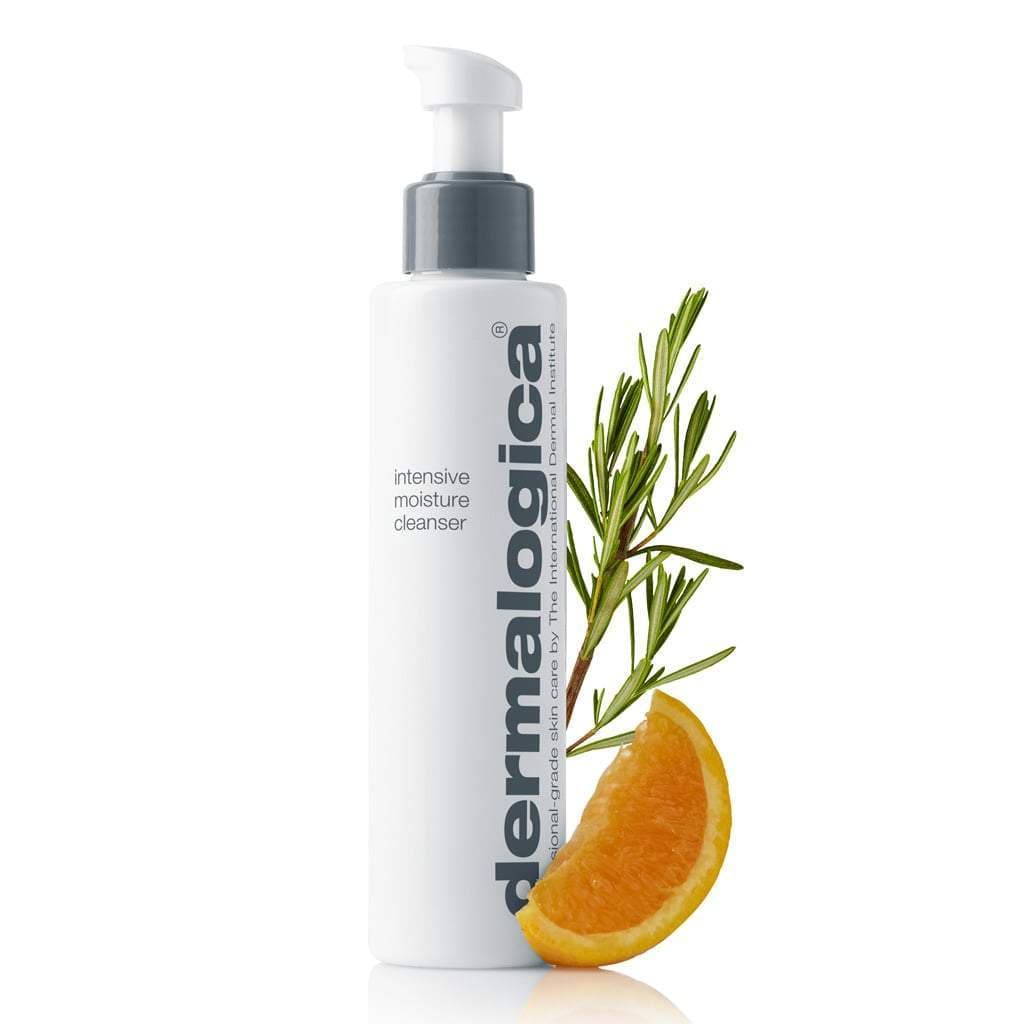 Flasche Intensive Moisture Cleanser mit Pumpspender, flankiert von einem Rosmarinzweig und einem Orangenschnitz auf weißem Hintergrund.