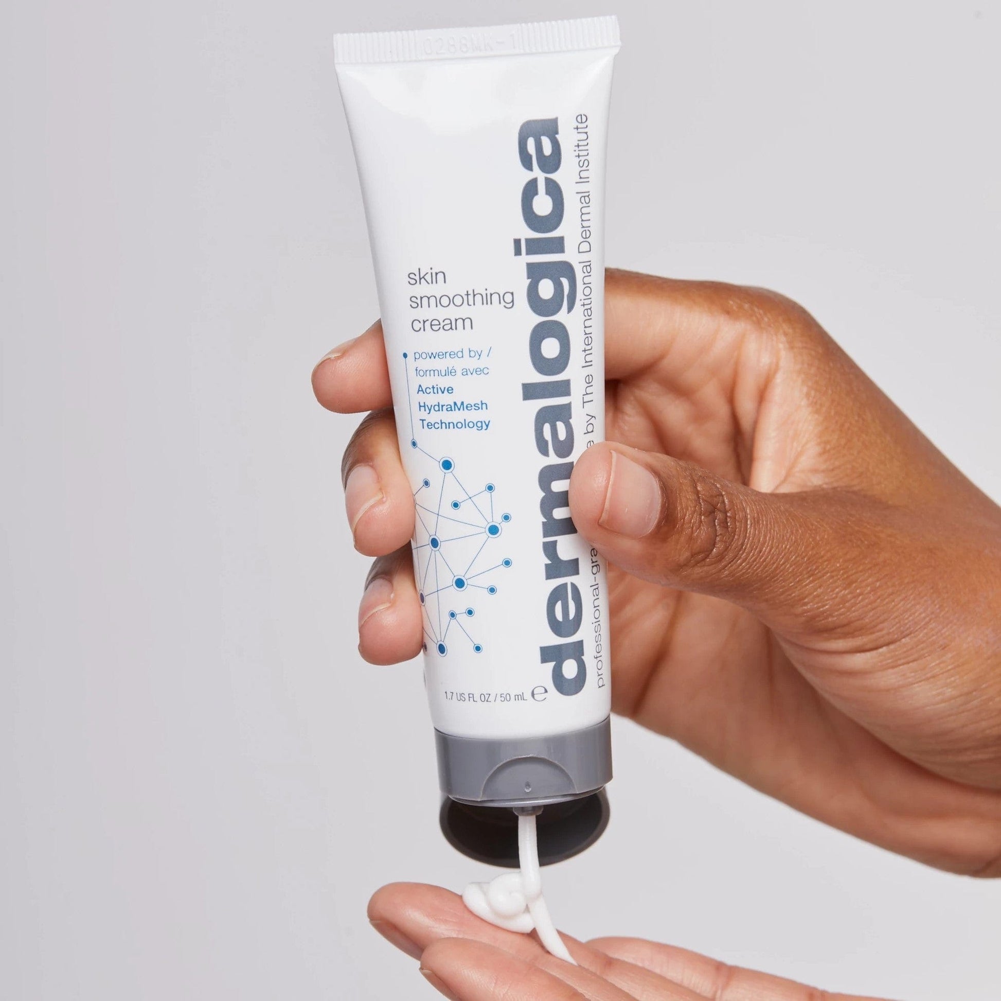 Eine Hand hält eine Tube Skin Smoothing Cream, aus der eine kleine Menge Creme gedrückt wird.